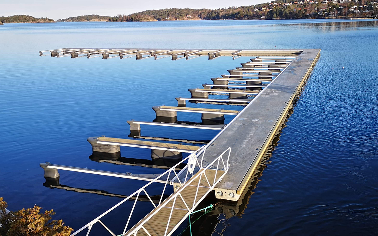 Marinaanlegg med betongbrygger og utriggermateriell på sjø